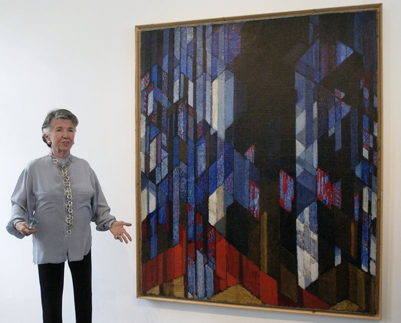 Meda Mládková, art collector and admirer of František Kupka's work, standing by his painting Cathedral.
